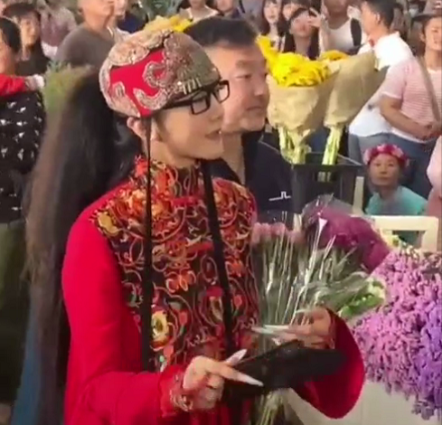 63岁杨丽萍一袭红衣逛花市被拍 男性友人贴心为其提袖子